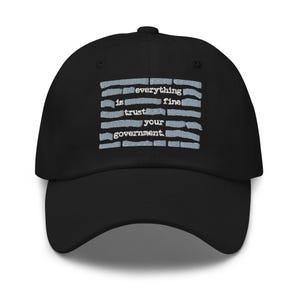 Puede incluir: Gorra de béisbol negra con el texto "everything is fine trust your government" en blanco. El texto está dispuesto en líneas horizontales con un fondo a rayas azul claro. La gorra tiene una visera curva y un botón en la parte superior.