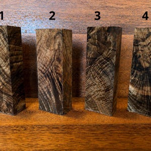 May include: Four rectangular wooden blocks arranged in a row, labelled with the numbers 1, 2, 3, and 4. Each block features a dark brown and black wood grain pattern with distinct swirling textures and natural variations throughout the surfaces.
