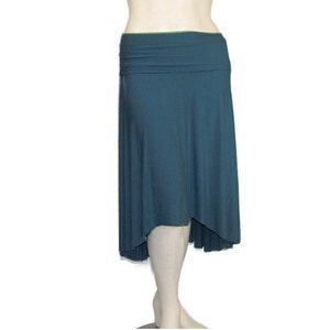 May include: A teal-colored skirt with a high waist and an asymmetrical hemline. The skirt is made of a soft, flowing fabric that drapes elegantly. The waistline is folded over, creating a layered effect. The skirt is designed to be comfortable and stylish.