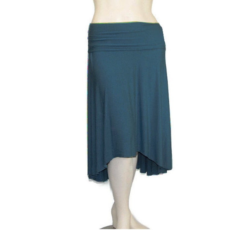 May include: A teal-colored skirt with a high waist and an asymmetrical hemline. The skirt is made of a soft, flowing fabric that drapes elegantly. The waistline is folded over, creating a layered effect. The skirt is designed to be comfortable and stylish.
