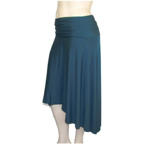 May include: A teal-colored asymmetrical skirt with a wide, ruched waistband. The skirt drapes to an uneven hemline, creating a flowing silhouette. The fabric appears soft and lightweight, suitable for casual wear.