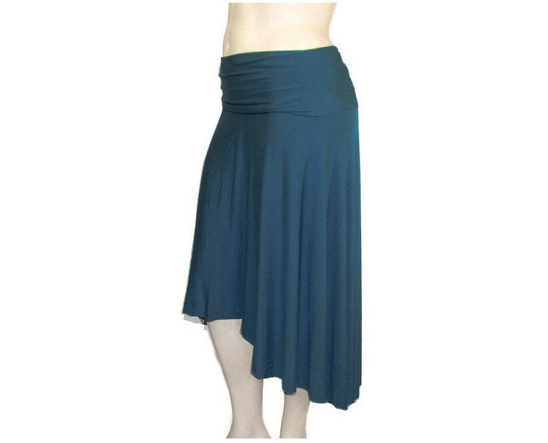 May include: A teal-colored asymmetrical skirt with a wide, ruched waistband. The skirt drapes to an uneven hemline, creating a flowing silhouette. The fabric appears soft and lightweight, suitable for casual wear.