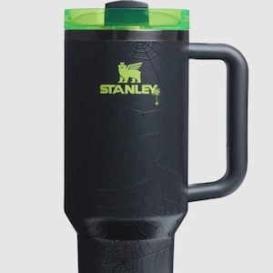 Puede incluir: Vaso Stanley negro con tapa y pajita verdes. El vaso presenta un dise&ntilde;o de telara&ntilde;a y el logotipo de Stanley en verde. Incluye un asa para facilitar su transporte.
