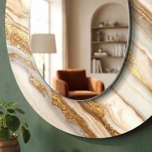 Peut inclure: Miroir ovale avec une bordure d&eacute;corative aux tons cr&egrave;me, or et marron, imitant le marbre. Le miroir a un fin cadre m&eacute;tallique argent&eacute;. Le reflet montre une pi&egrave;ce avec une chaise, une lampe et une biblioth&egrave;que.