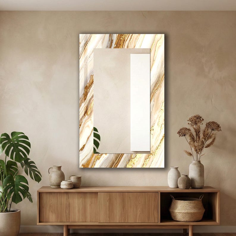 Peut inclure: Miroir mural rectangulaire avec un cadre effet marbre aux tons dor&eacute;s et beiges. Le miroir est suspendu au-dessus d'un meuble en bois avec des vases et un panier tress&eacute;. Une plante en pot est visible &agrave; gauche.