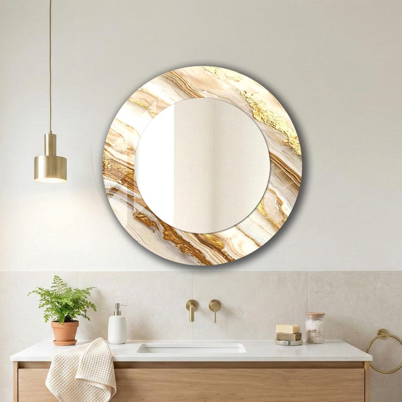 Peut inclure: Un miroir mural rond avec un motif marbr&eacute;. Le cadre pr&eacute;sente un m&eacute;lange de blanc, d'or et de brun, cr&eacute;ant une esth&eacute;tique luxueuse. Le miroir est install&eacute; au-dessus d'un meuble de salle de bain.