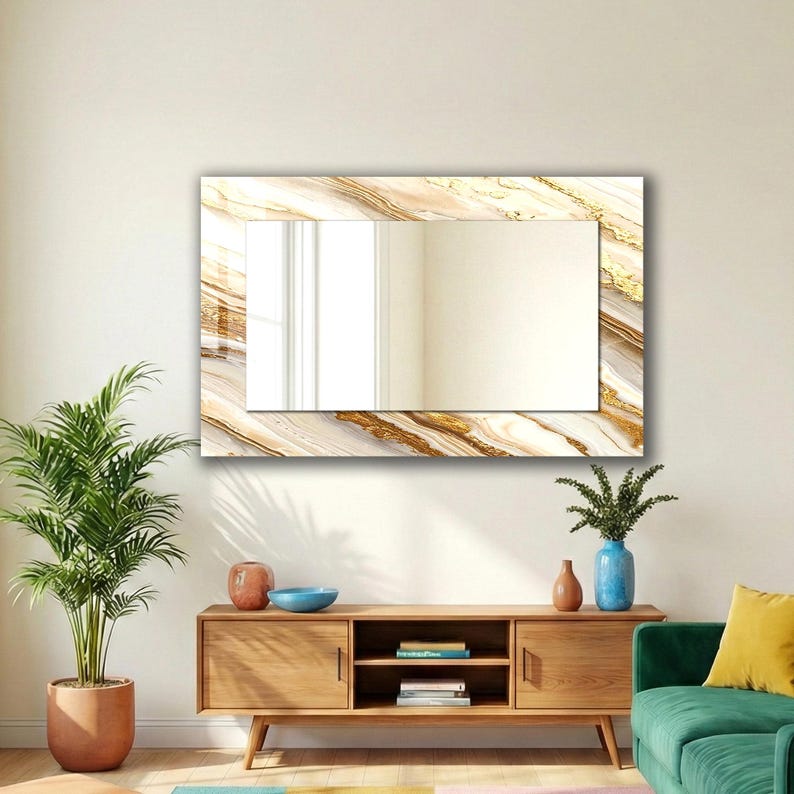 Peut inclure: Un miroir mural rectangulaire avec un cadre effet marbre aux tons dor&eacute;s et beiges. Le miroir est fix&eacute; sur un mur blanc. Un meuble en bois est en dessous. Une plante en pot est &agrave; gauche.