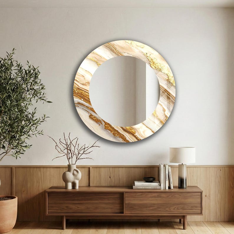 Peut inclure: Miroir rond d&eacute;coratif avec un motif marbr&eacute; blanc, beige et dor&eacute;. Le miroir est accroch&eacute; &agrave; un mur blanc au-dessus d'un meuble en bois. Le cadre pr&eacute;sente un aspect textur&eacute;. Le diam&egrave;tre du miroir est d'environ 60 cm.