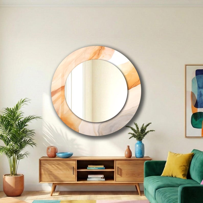Op de afbeelding: Een ronde wandspiegel met een brede, cirkelvormige lijst versierd met een vloeiend, abstract patroon in zachte tinten oranje, beige en cr&egrave;me. Het centrale reflecterende glazen oppervlak is cirkelvormig en biedt een helder beeld.
