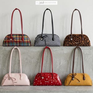 May include: Collection of six handbags with long handles. The bags feature various patterns and colors, including plaid, gingham, leopard print, pink, red with white stars, and mustard yellow. Each bag has a bow and heart-shaped charm.