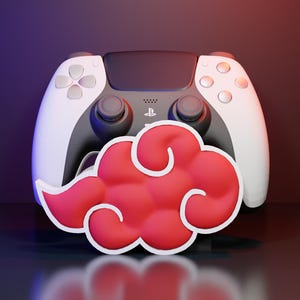 Peut inclure: Une manette de jeu vidéo noire et blanche avec un emblème de nuage rouge proéminent doté d'un contour blanc placé au premier plan. La manette possède deux joysticks analogiques, une croix directionnelle et le logo PlayStation sur le pavé tactile.