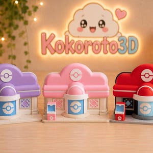 Può includere: Tre edifici in miniatura del Centro Pokémon in viola, rosa e rosso, ciascuno caratterizzato da un emblema centrale Poké Ball, un ingresso azzurro e un piccolo videogioco arcade abbinato. Le strutture poggiano su una base piatta piastrellata.