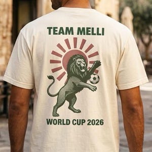 Ivory Comfort Colors heavyweight t-shirt with vintage Iran Lion and Sun World Cup 2026 badge on front chest and Team Melli vintage poster design on back, made for Iranian diaspora soccer fans.