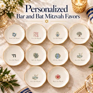 May include: Ten small, round, off-white ceramic trinket dishes with gold-painted rims, each featuring unique colorful illustrations and personalized text. The text reads Personalized Bar and Bat Mitzvah Favors at the top of the image.