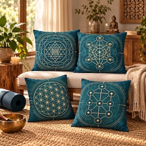 May include: A set of four square throw pillows in a deep teal color, each featuring a distinct gold-colored geometric pattern. The designs include a Sri Yantra, a Metatron's cube, a flower of life, and a tree of life motif printed on the fabric.