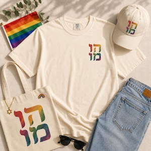 Könnte beinhalten: Ein cremefarbenes T-Shirt, eine passende Baseballkappe und eine Stofftasche, alle mit dem hebräischen Text "הומו" in einem Regenbogenverlauf. Eine kleine Regenbogenflagge, eine goldene Davidstern-Halskette und eine schwarze Sonnenbrille sind dabei.