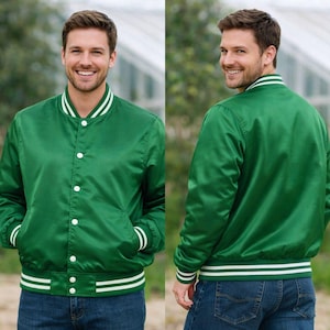 May include: A green satin bomber jacket with white stripes on the collar, cuffs, and hem. The jacket has a button-up front and two front pockets. The model is wearing blue jeans.