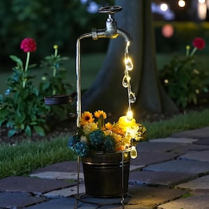 Puede incluir: Escultura decorativa de grifo de agua para exteriores con un cubo de flores. El grifo es de metal y tiene un aspecto vintage. El agua parece fluir del grifo como una cadena de luces. El cubo contiene flores amarillas, azules y naranjas.