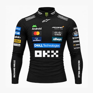 Puede incluir: Una camiseta negra de manga larga con cuello alto que presenta varios logotipos de patrocinadores, incluidos McLaren, Android, Dell Technologies, OKX, Hilton y Richard Mille. La prenda tiene un corte ajustado con marcas blancas y de colores.