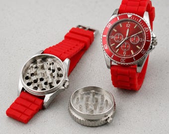 May include: A red wristwatch with a silicone strap and a circular face featuring a red dial with silver hands and markers. Beside it, a disassembled watch-shaped grinder reveals a metallic interior with sharp teeth for grinding herbs.