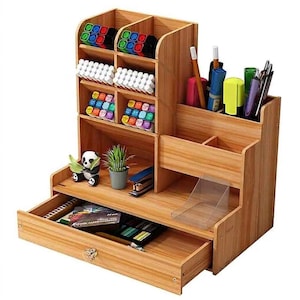 May include: A wooden desk organizer with multiple compartments and a drawer. The organizer is filled with pens, markers, and other office supplies. A small panda figurine and a potted plant are on the top shelf. The organizer is made of light brown wood.