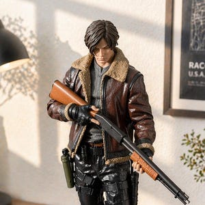 May include: A detailed action figure of a character with brown hair, wearing a brown leather jacket with a tan shearling collar, a gray shirt, and black tactical pants. The figure holds a shotgun and stands on a circular black base.