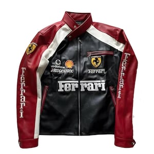 May include: A black, red, and white Ferrari racing jacket. The jacket features the Ferrari logo, sponsor logos, and the word "Ferrari" in white lettering. The sleeves are red with white lettering. The jacket has a zipper closure.