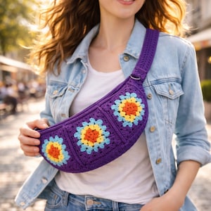 Può includere: Marsupio all'uncinetto viola con tre disegni floreali gialli, arancioni e azzurri. La borsa ha una tracolla abbinata e un anello di metallo color argento. La borsa è indossata a tracolla.