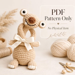 Peut inclure: Une créature beige crochetée avec de grands yeux ronds et un visage souriant. Elle a un corps torsadé et un nœud crème. Le texte "PDF Pattern Only" est affiché, indiquant un produit numérique.