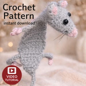 May include: A crocheted gray rat with pink ears and paws, black eyes, and whiskers. The image includes the text "Crochet Pattern instant download" and a video tutorial icon. The rat is posed as if standing.