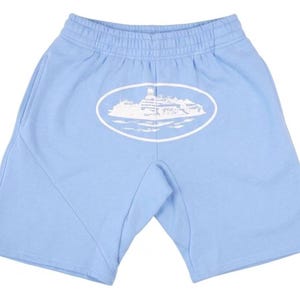 K&ouml;nnte beinhalten: Hellblaue Shorts mit elastischem Bund und Seitentaschen. Auf der Vorderseite ist ein wei&szlig;es ovales Motiv mit einem Geb&auml;ude und Wasser aufgedruckt. Die Shorts sind aus weichem Material.