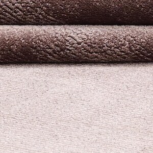 Puede incluir: Primer plano de una tela texturizada en tonos marr&oacute;n y beige. La parte superior presenta dos capas dobladas de un material afelpado y aterciopelado, mientras que la parte inferior muestra una tela m&aacute;s lisa y de color m&aacute;s claro. Las texturas crean un efecto de capas.