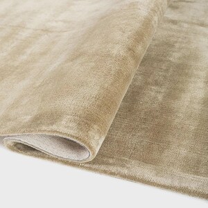 Pu&ograve; includere: Un tappeto beige arrotolato, con una texture morbida e soffice. Le fibre del tappeto creano una sottile lucentezza e il lato inferiore &egrave; di una tonalit&agrave; pi&ugrave; chiara e neutra. Il tappeto &egrave; probabilmente realizzato in un materiale morbido.