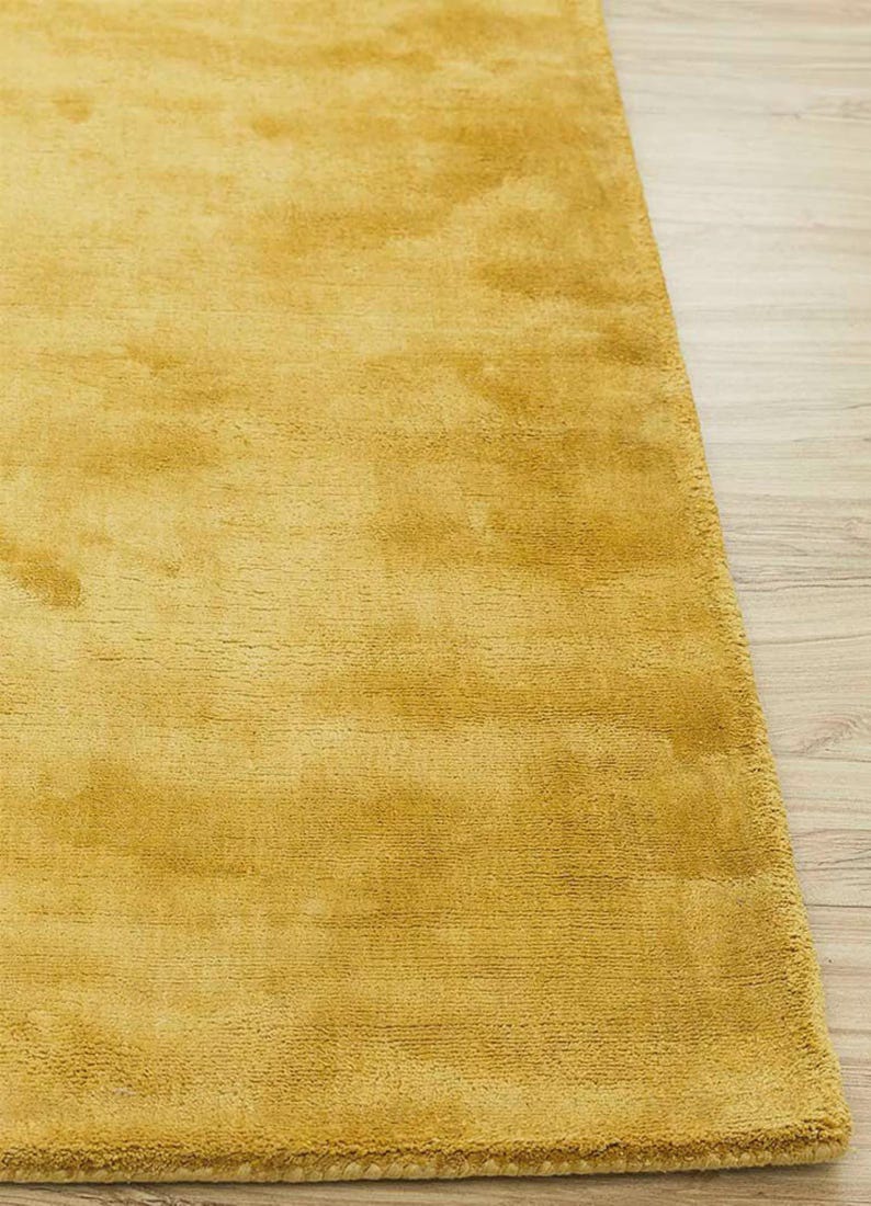 May include: Mustard yellow area rug with a soft, textured surface. The rug is rectangular and has a plush appearance, suitable for a living room or bedroom. The rug's color is a warm, inviting tone.