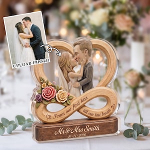 May include: A personalized wedding keepsake featuring a kissing couple figurine within a wooden heart-shaped frame. The base includes the names "Mr & Mrs Smith" and the date "16-11-2026". The text "From our first kiss till our last breath" is also included.