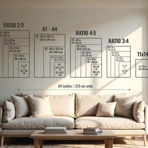 May include: A wall display showing print size ratios and dimensions in inches and centimeters. The ratios include 2:3, A1-A4, 4:5, 3:4, and 11x14. The display is above a beige sofa with pillows and a wooden coffee table.