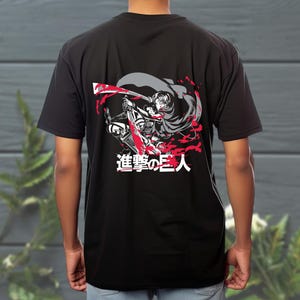 May include: Black t-shirt with a graphic from the anime Attack on Titan. The design shows a character in action with red and grey details, and Japanese text. The shirt is a short-sleeved crew neck.