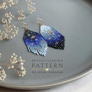 Puede incluir: Un par de pendientes de flecos hechos con cuentas que presentan un degradado de color desde azul claro hasta azul oscuro y negro, acentuados con pequeñas cuentas doradas. El texto BEADED EARRING PATTERN PDF INSTANT DOWNLOAD aparece debajo.