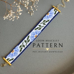May include: A beaded loom bracelet pattern featuring a floral design in shades of blue, white, and green. The bracelet has gold-colored metal ends and a chain clasp. The text "LOOM BRACELET PATTERN" is displayed.