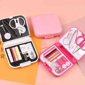 May include: Miniature sewing kits in white and pink cases. Each kit contains scissors, needles, thread, and buttons. The kits are open, revealing the contents, with one closed pink case in the background. The background is a light orange and pink.