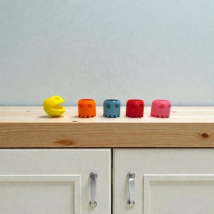 Puede incluir: Una taza de cerámica blanca con un asa negra y el texto "But First, Coffee" en negrita negra. La taza está sobre un fondo borroso. La taza mide aproximadamente 10 cm de altura.