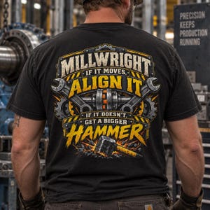 May include: A black t-shirt featuring a graphic on the back with the text MILLWRIGHT IF IT MOVES, ALIGN IT IF IT DOESN'T, GET A BIGGER HAMMER. The design includes illustrations of a mechanical shaft, two wrenches, gears, and a large hammer.