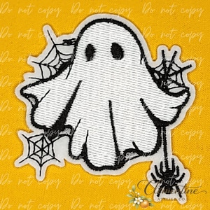 May include: An embroidered patch featuring a white ghost with black eyes and outlines. The ghost is surrounded by black spiderwebs and a small black spider hanging from the bottom right. The design has a white border and a textured fabric finish.