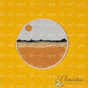 May include: A circular embroidered patch featuring a landscape design. The top section shows a light grey sky with a small orange sun, a dark green horizon line, and a bottom section filled with textured horizontal rows of golden orange thread.