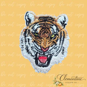 Può includere: Toppa ricamata a forma di testa di tigre con cuciture dettagliate nei toni del marrone, arancione, nero e bianco. La tigre ha la bocca aperta, rivelando una lingua rossa e denti affilati. Lo sfondo è giallo pieno con il testo "Do not copy" ripetuto.