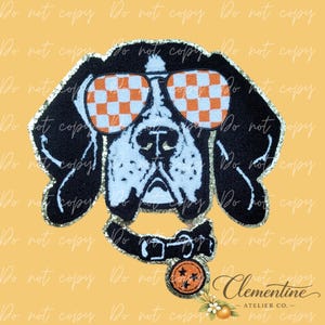 May include: A chenille patch featuring a black and white dog head wearing orange and white checkered sunglasses. The dog has a black collar with a round orange tag featuring three black stars. The patch has a gold glitter border.