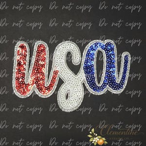 Op de afbeelding: Een paillettenapplicatie met de letters USA in cursief schrift. De letter U is rood, de letter S is wit en de letter A is blauw. Elke letter is omlijnd met zilveren pailletten, wat zorgt voor een patriottisch ontwerp met een glinsterende textuur.