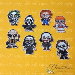 May include: A collection of eight embroidered patches featuring stylized horror movie characters, including a green-haired figure, a masked ghost, a doll in overalls, a doll in a white dress, a hockey-masked figure, a nun, a puppet, and a man with a knife.