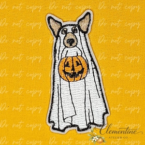 May include: An embroidered patch featuring a dog wearing a white ghost costume. The dog has pointed ears and a tan snout, and it is holding a bright orange jack-o'-lantern pumpkin with a carved face. The design uses black outlines on white fabric.
