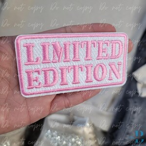 Puede incluir: Un parche rectangular con las palabras "LIMITED EDITION" bordadas en hilo rosa sobre un fondo blanco. El parche tiene un borde rosa y está diseñado para coserlo en ropa o accesorios.
